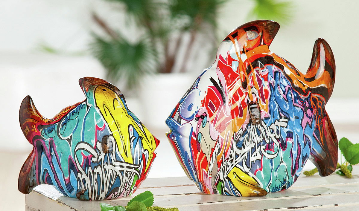 Zwei bunte Fischskulpturen im Street-Art-Stil auf einem Tisch, seitliche Perspektive