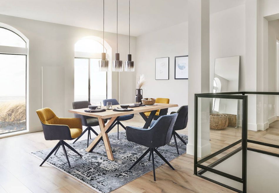 Moderner Esstisch mit Holztischplatte und X-förmigen Beinen, umgeben von stilvollen Stühlen in einem hellen, eleganten Esszimmer. Perspektive von der Seite.