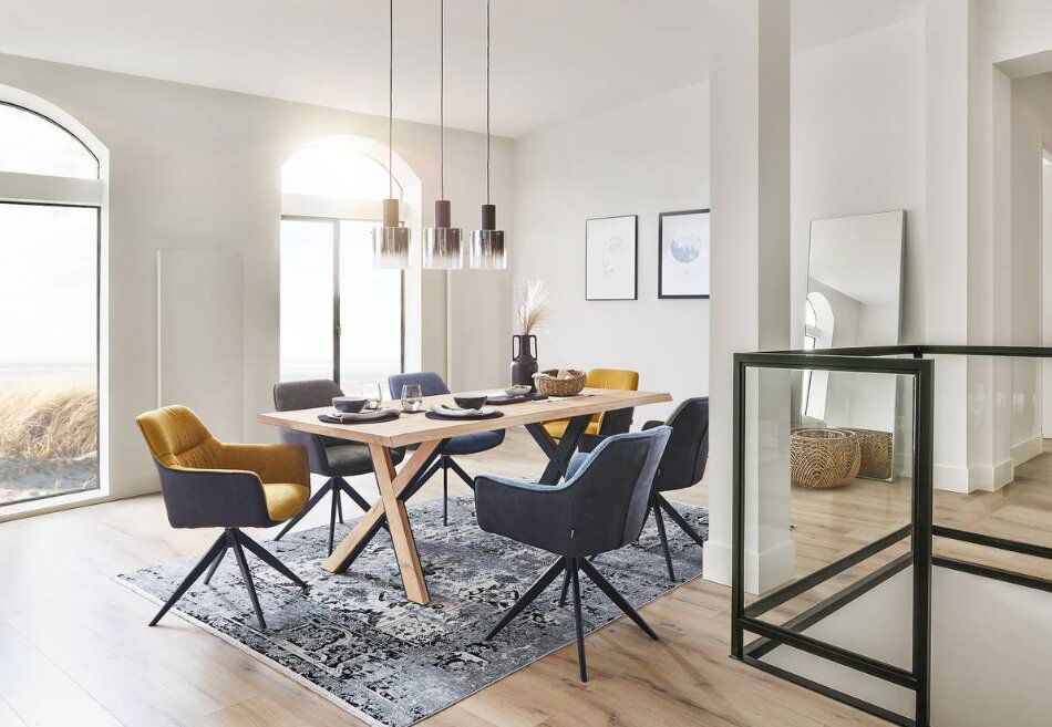 Moderner Esstisch mit Holztischplatte und X-förmigen Beinen, umgeben von stilvollen Stühlen in einem hellen, eleganten Esszimmer. Perspektive von der Seite.