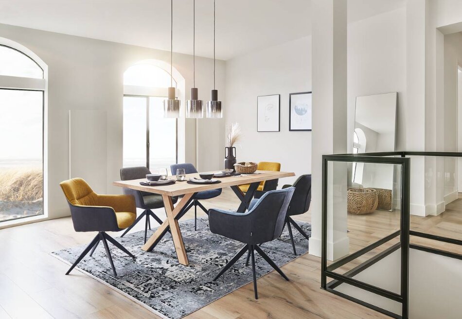 Moderner Esstisch mit Holztischplatte und X-förmigen Beinen, umgeben von stilvollen Stühlen in einem hellen, eleganten Esszimmer. Perspektive von der Seite.