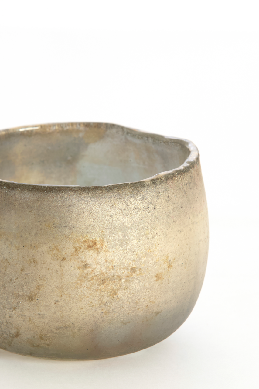 Nahaufnahme eines rustikalen, goldfarbenen Teelichthalters mit unregelmäßiger Oberfläche und leicht ungleichmäßigem Rand.