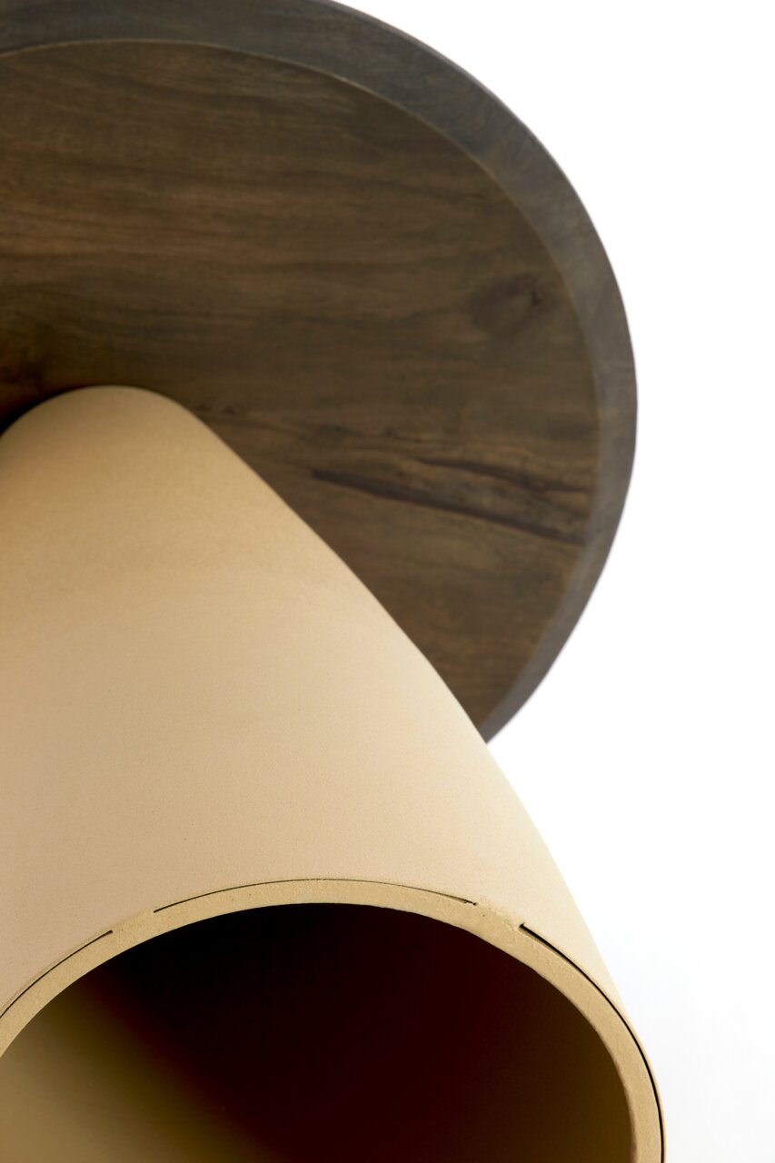 Nahaufnahme eines Beistelltisches von unten, mit einer runden Holzplatte und einem konischen, beigen Sockel.