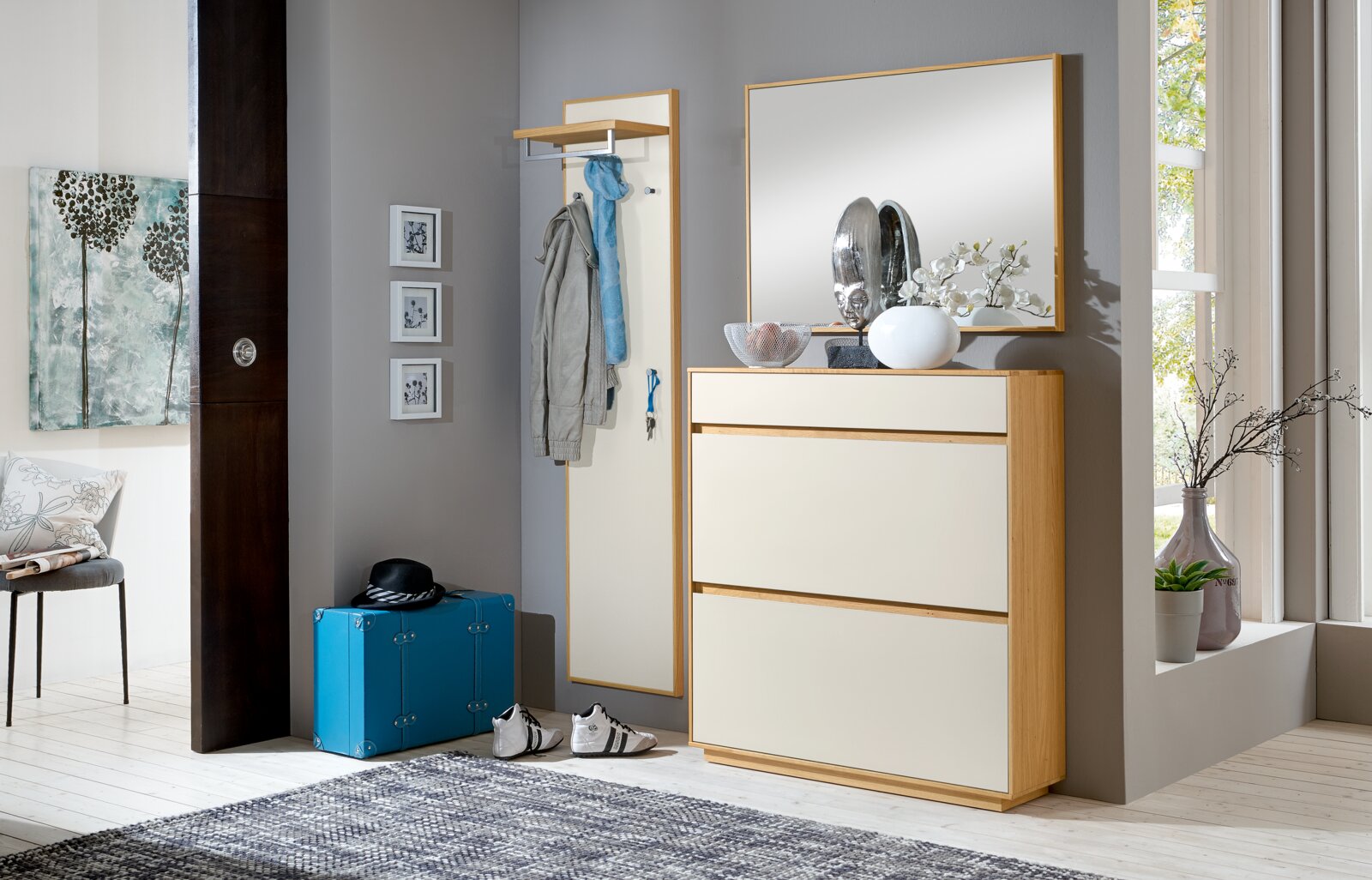 Modernes Flur-Set mit Schuhschrank in Holz-Optik und weißen Fronten, großem Wandspiegel und Garderobenpaneel mit Ablage und Haken, fotografiert in leichter Schrägansicht von vorne rechts.