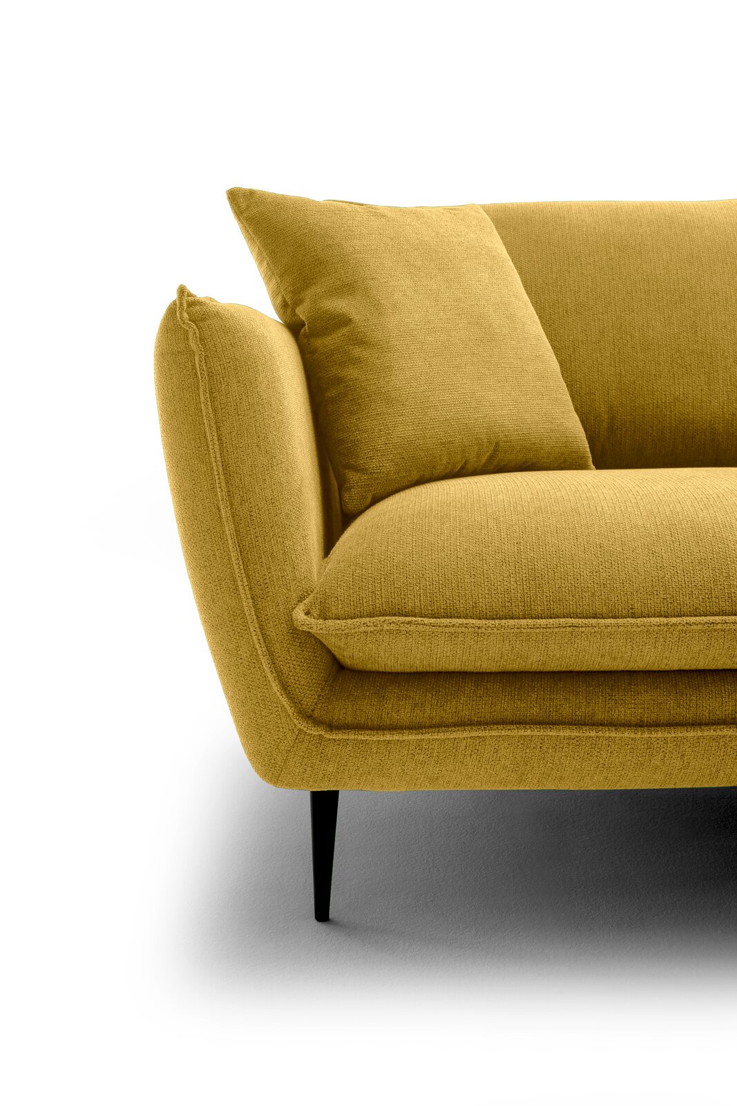 Nahaufnahme eines senfgelben Stoffsofas mit Armlehne, Sitzkissen und Rückenkissen auf schwarzen, schlanken Beinen, freigestellt auf weißem Hintergrund; Perspektive: schräg von vorne links.