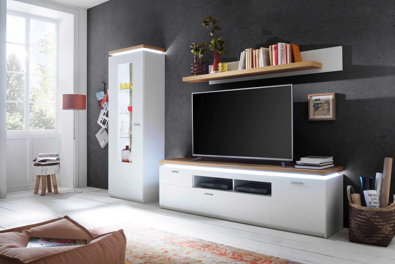 Moderne Wohnwand mit Vitrine, TV-Element und Wandboard in heller, stilvoller Umgebung, seitliche Perspektive.