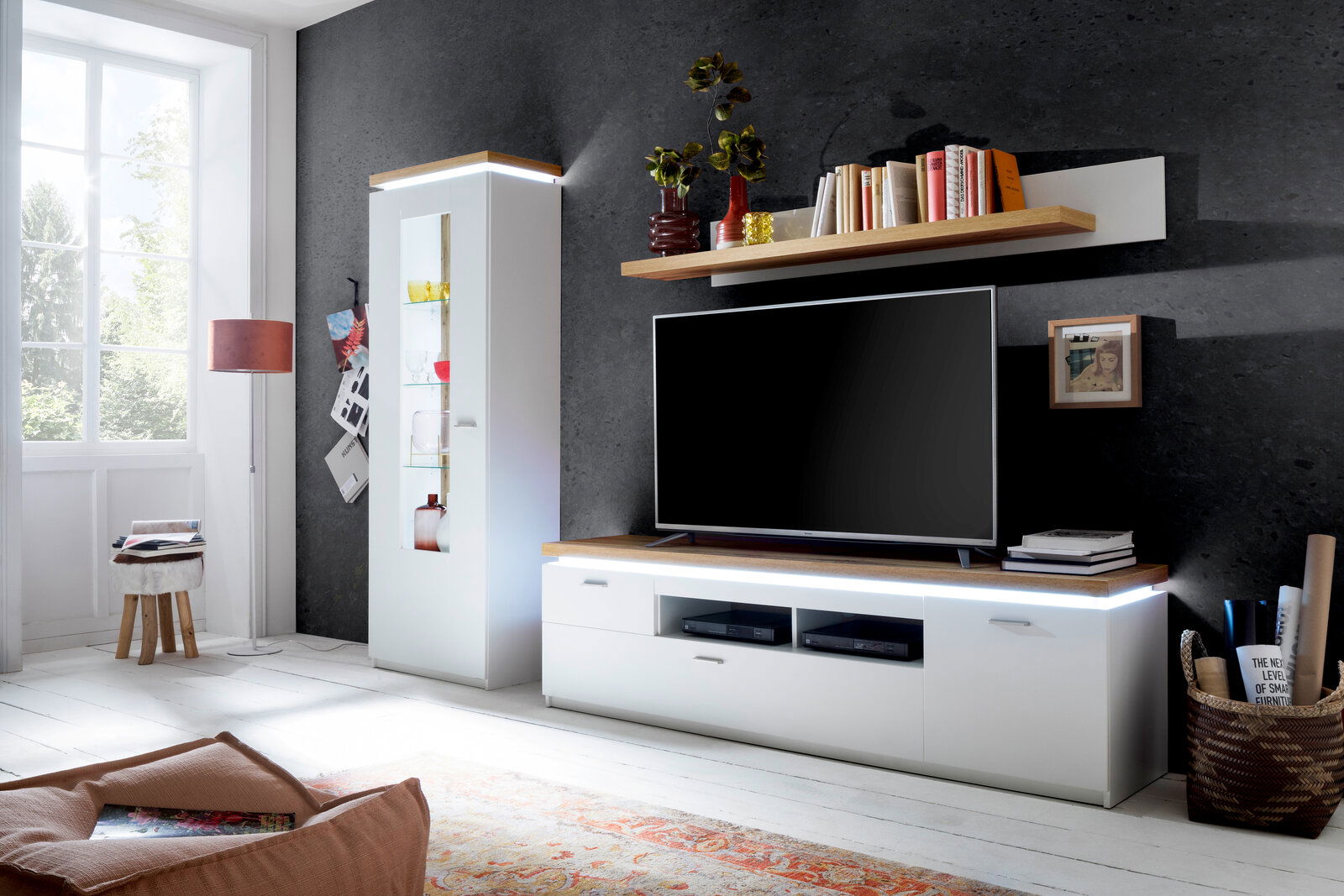 Moderne Wohnwand mit Vitrine, TV-Element und Wandboard in heller, stilvoller Umgebung, seitliche Perspektive.