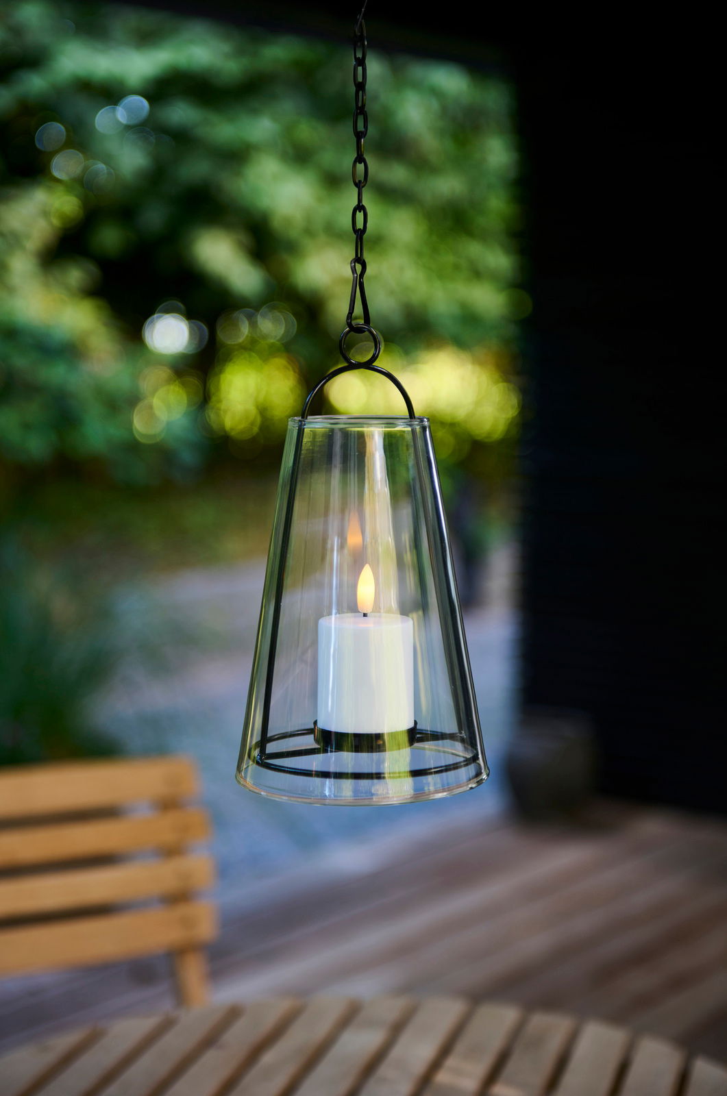 Hängendes Windlicht mit LED-Kerze in einem Garten, seitliche Perspektive