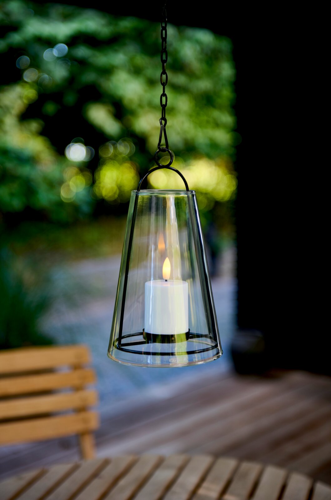 Hangende windlicht met led-kaars in een tuin, zijaanzicht