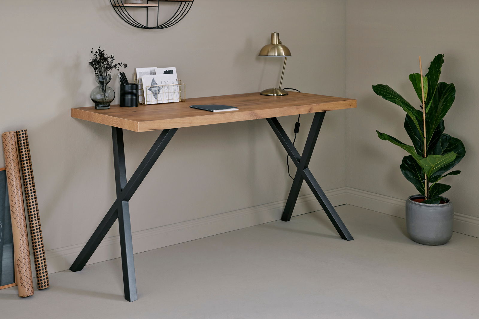 Moderner Schreibtisch mit Holzplatte und schwarzen Metallbeinen, seitliche Perspektive, dekoriert mit Lampe, Pflanzen und Schreibutensilien.