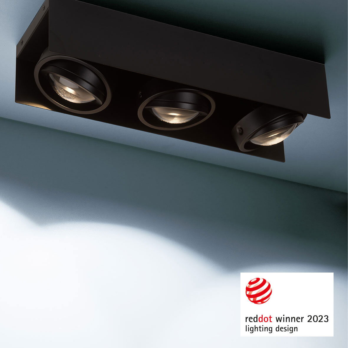 Moderne LED Aufbauleuchte mit drei runden Strahlern in schwarzem Gehäuse, von unten betrachtet. Gewinner des Red Dot Design Awards 2023.
