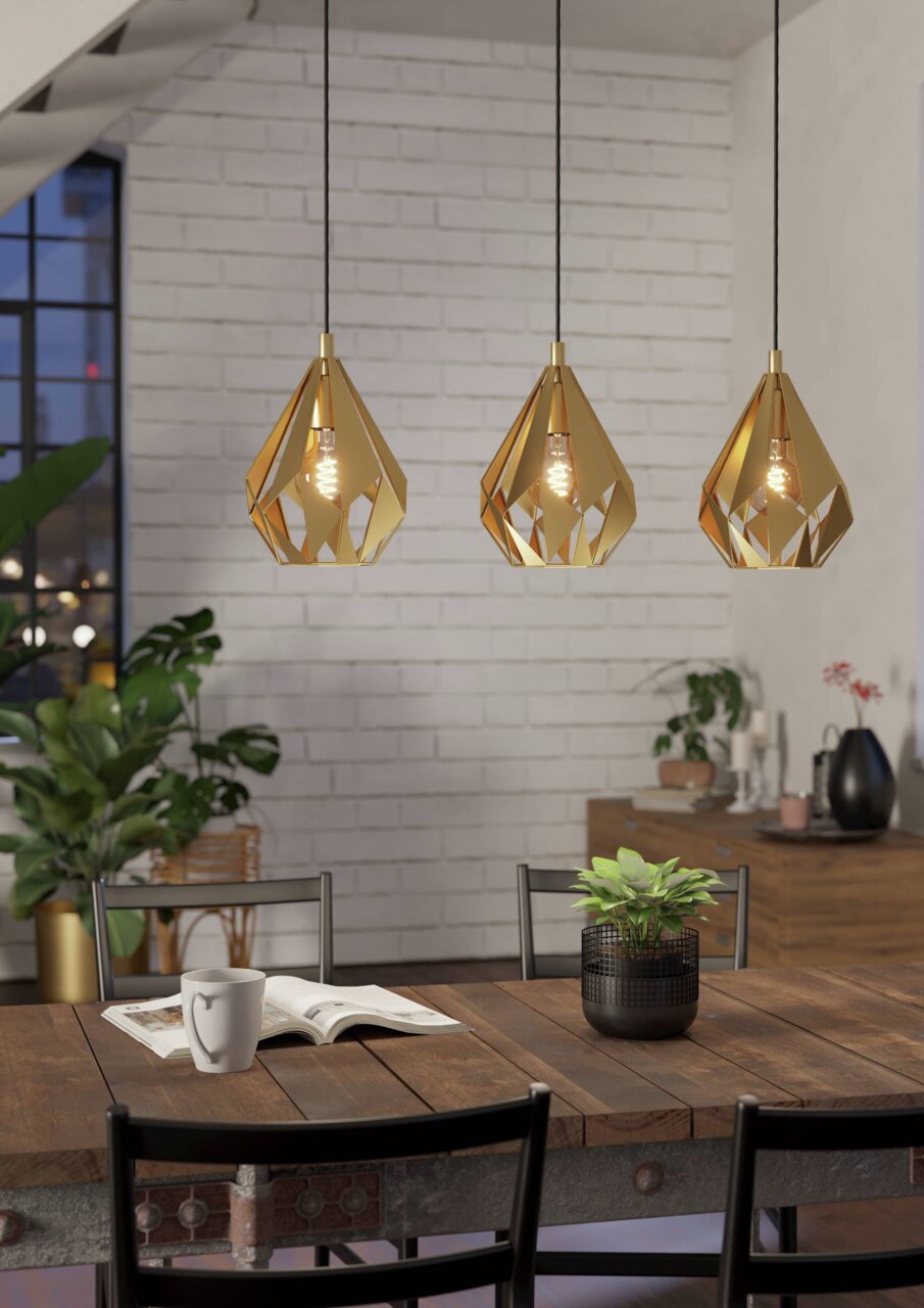 Drei goldene Pendelleuchten CARLTON hängen über einem Esstisch in einem modernen Esszimmer, seitliche Perspektive.