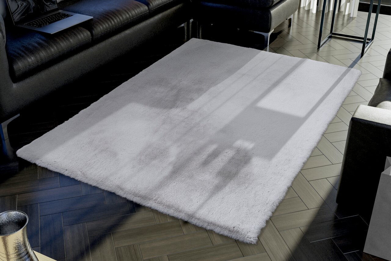 Ein weißer Fellteppich liegt in einem modernen Wohnzimmer auf einem dunklen Holzboden. Die Perspektive zeigt den Teppich von schräg oben, umgeben von einem schwarzen Ledersofa und einem Tisch.