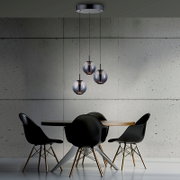 Moderne LED-Pendelleuchte mit drei kugelförmigen Lampenschirmen, hängend über einem Esstisch in einem stilvollen, minimalistischen Raum. Perspektive von vorne.