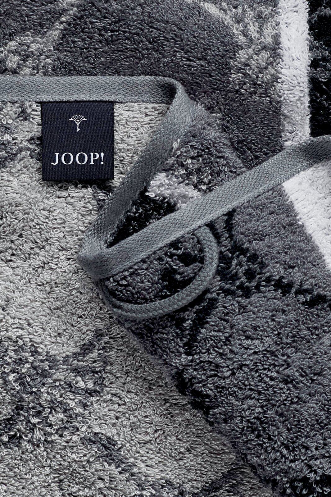 Grijze handdoek met ingeweven patroon en JOOP!-label, close-up
