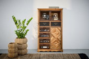 Kommode aus Holz mit verschiedenen Schubladen und Türen, dekoriert mit Aufdrucken und Mustern, frontal fotografiert. Daneben steht eine Pflanze in einem geflochtenen Korb.