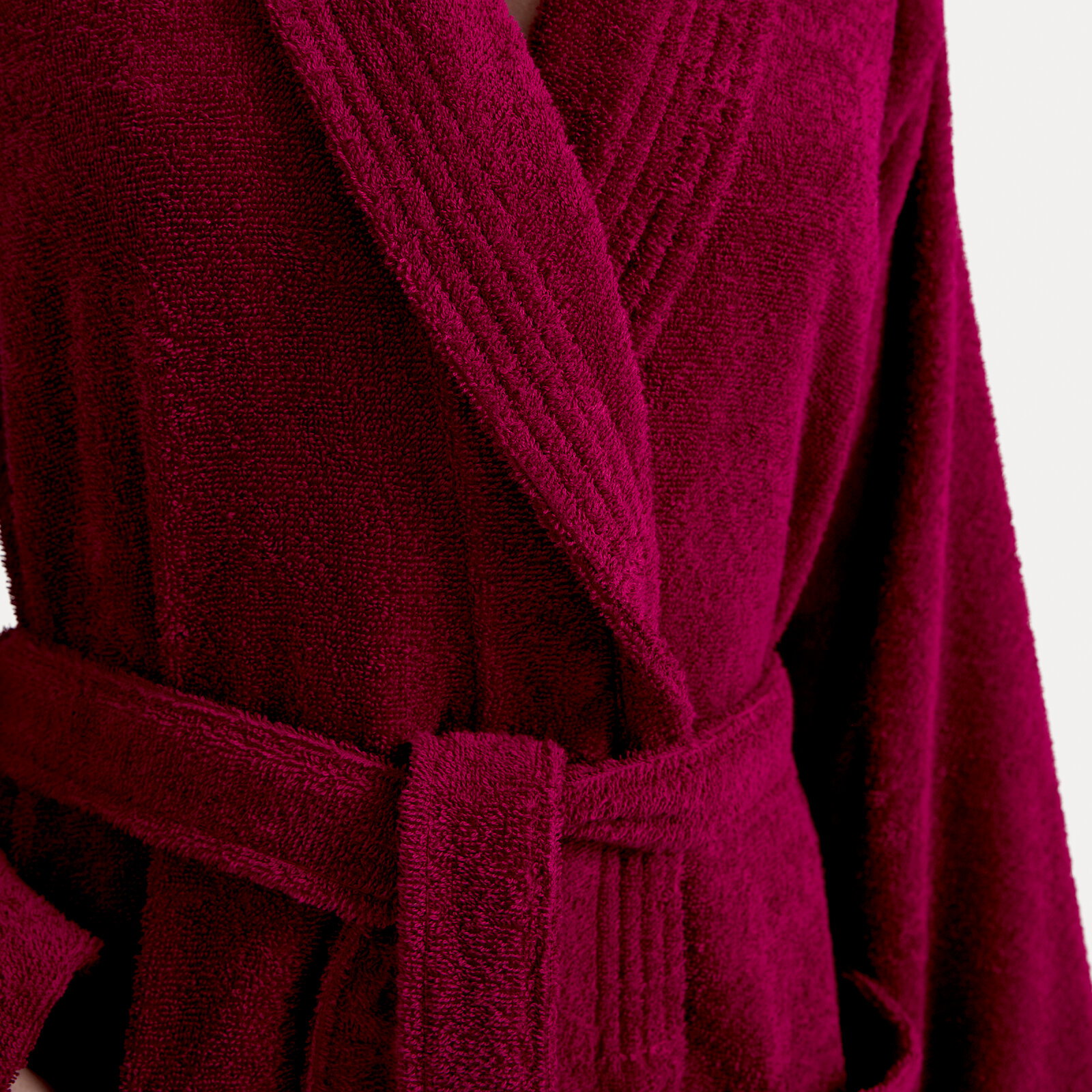 Nahaufnahme eines weinroten Bademantels mit Schalkragen und Gürtel, Vorderansicht.