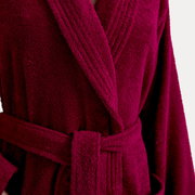 Nahaufnahme eines weinroten Bademantels mit Schalkragen und Gürtel, Vorderansicht.