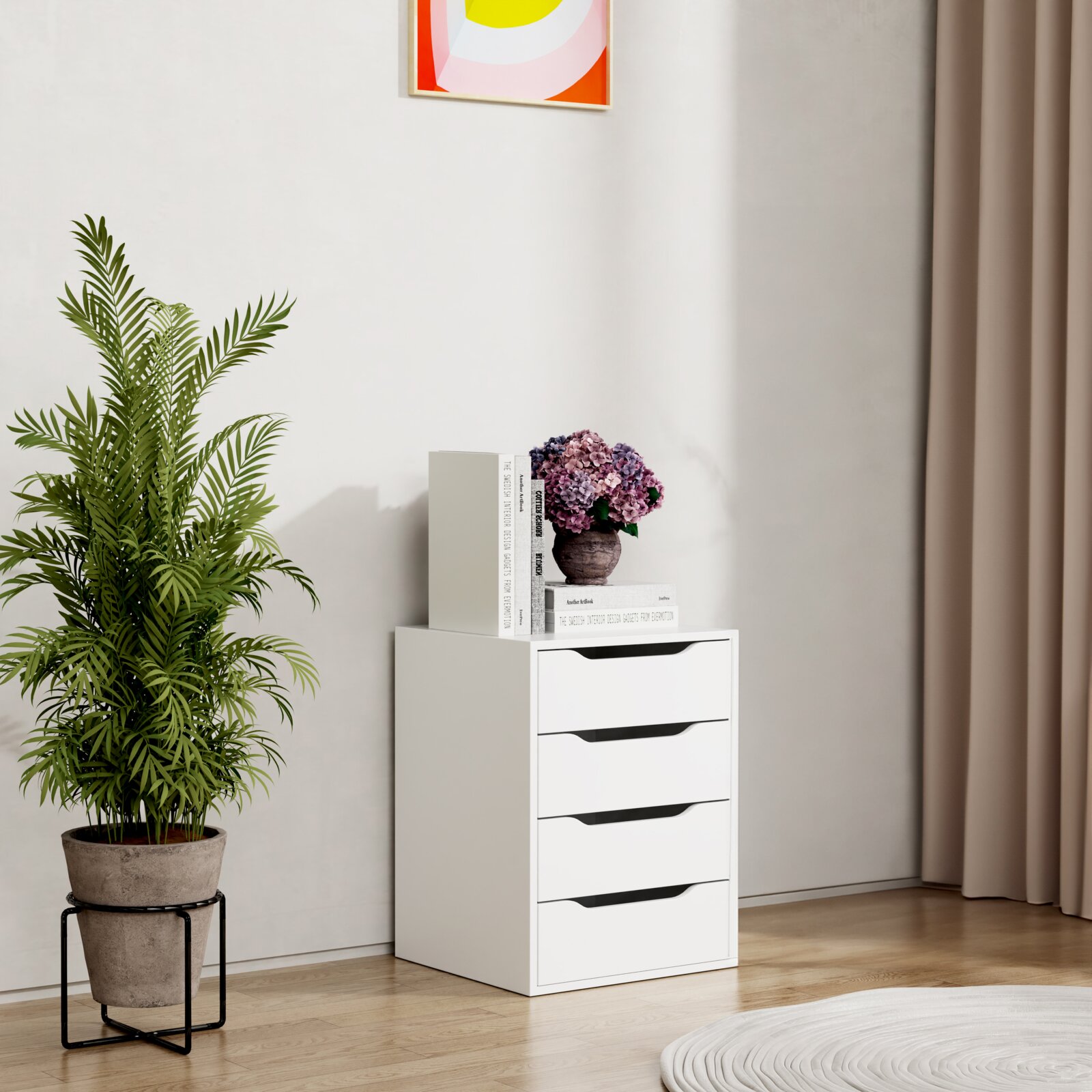 Weiße Kommode mit vier Schubladen und schwarzen Griffmulden in modernem Wohnraum, auf der Ablage Bücher und eine Vase mit Hortensien; frontale Ansicht mit leichtem Blick von links.