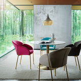 Esszimmer mit modernem Design, bestehend aus einem runden Tisch und bunten Sesseln der Serie SUNNY von Livetastic. Die Perspektive zeigt den Raum mit großen Fenstern, die einen Blick auf einen grünen Wald bieten.
