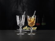 Zwei elegante Cocktailgläser mit Strohhalmen, eines leer und eines mit Getränk und Limettenscheibe, auf schwarzem Hintergrund, seitliche Perspektive.