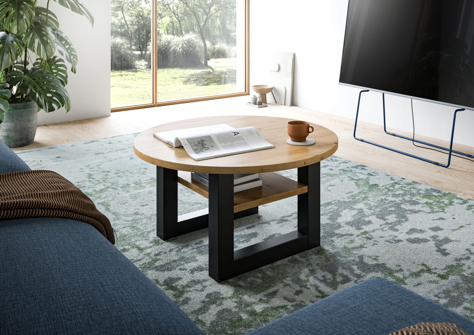 MID.YOU Couchtisch SEATTLE Runder Couchtisch aus Holz mit schwarzem Metallgestell, von schräg oben fotografiert, auf einem gemusterten Teppich in einem modernen Wohnzimmer.