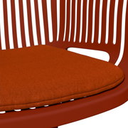 Nahaufnahme eines roten Stapelsessels mit gepolstertem Sitzkissen, seitliche Perspektive