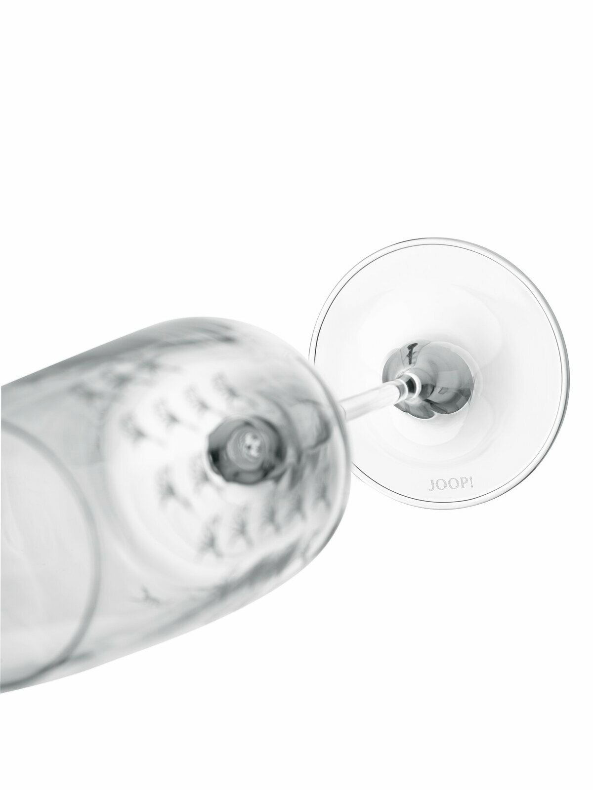 Nahaufnahme eines umgekippten Champagnerglases mit der Aufschrift 'JOOP!' auf dem Glasboden, von oben betrachtet.