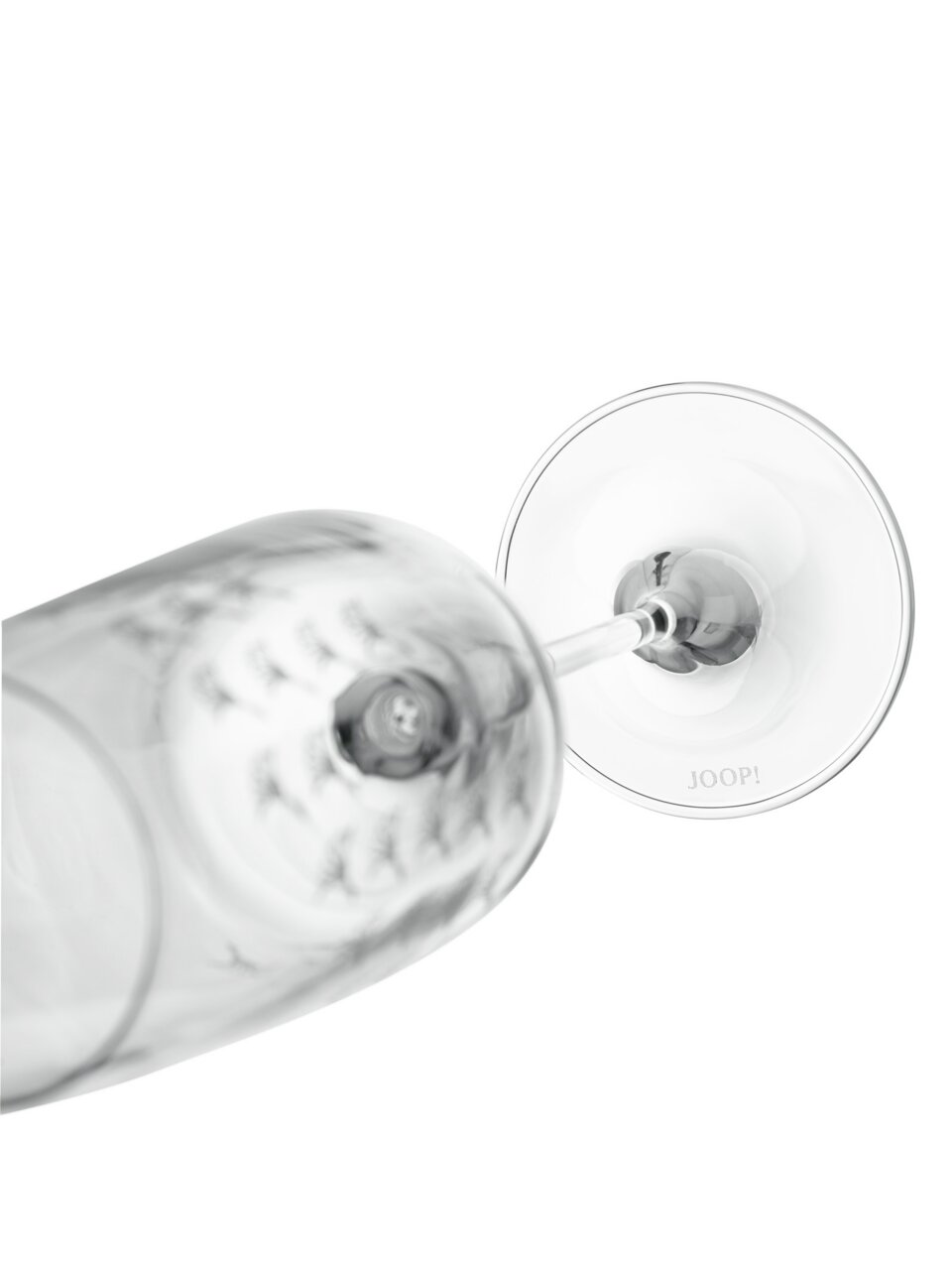 Nahaufnahme eines umgekippten Champagnerglases mit der Aufschrift 'JOOP!' auf dem Glasboden, von oben betrachtet.