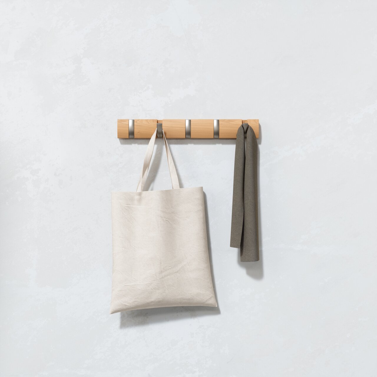 Wandgarderobe aus Holz mit fünf Haken, an der eine Stofftasche und ein Schal hängen, frontal betrachtet.