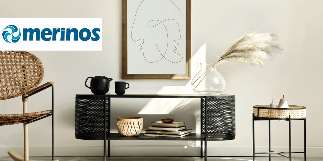 Ein moderner Raum mit einem geflochtenen Stuhl, schwarzen Möbeln mit dem Merinos-Logo in der Ecke.