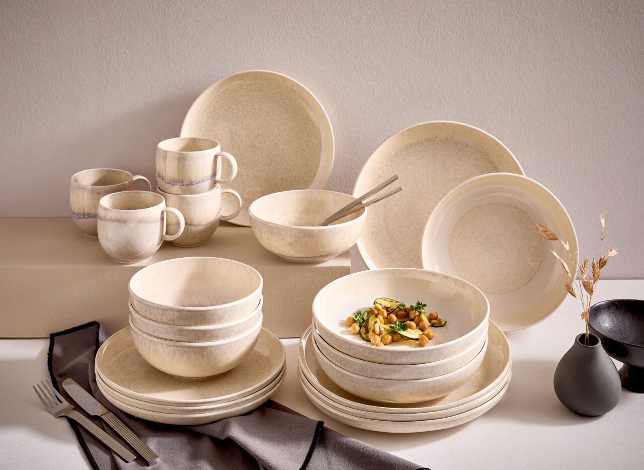 Tafelservice 8-tlg. in natürlichem Beige-Ton, bestehend aus Tellern, Schalen und Tassen, aus seitlicher Perspektive fotografiert.