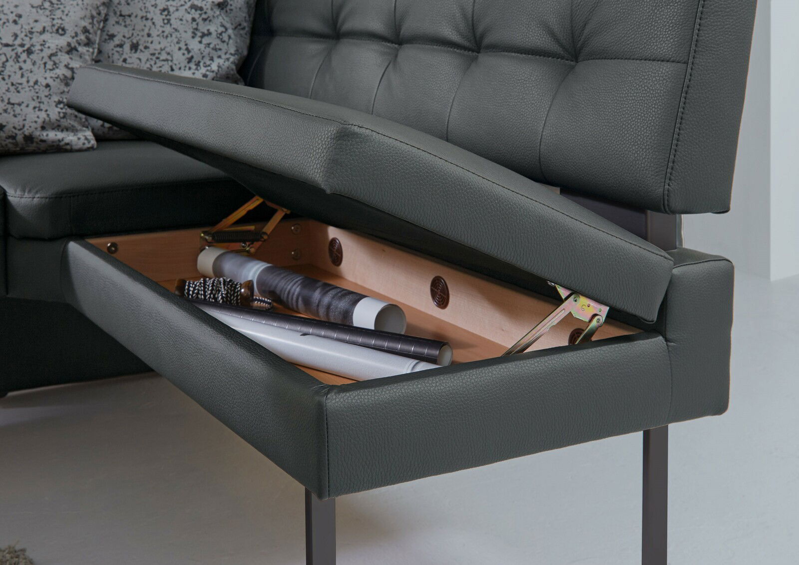 Dieter Knoll Eckbank LIMONE Detailansicht einer Eckbank mit aufklappbarem Stauraum unter der Sitzfläche, in dem verschiedene Gegenstände aufbewahrt werden.