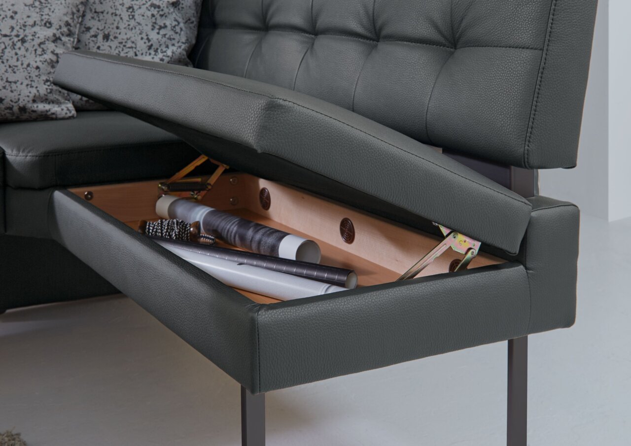 Dieter Knoll Eckbank LIMONE Detailansicht einer Eckbank mit aufklappbarem Stauraum unter der Sitzfläche, in dem verschiedene Gegenstände aufbewahrt werden.