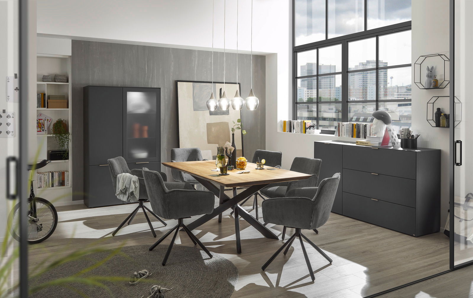 Esszimmer mit modernem Design, bestehend aus einem Holztisch und sechs drehbaren Armlehnstühlen der Serie FRISCO von Musterring. Die Perspektive zeigt den Raum von der Seite mit Blick auf den Tisch und die Stühle.