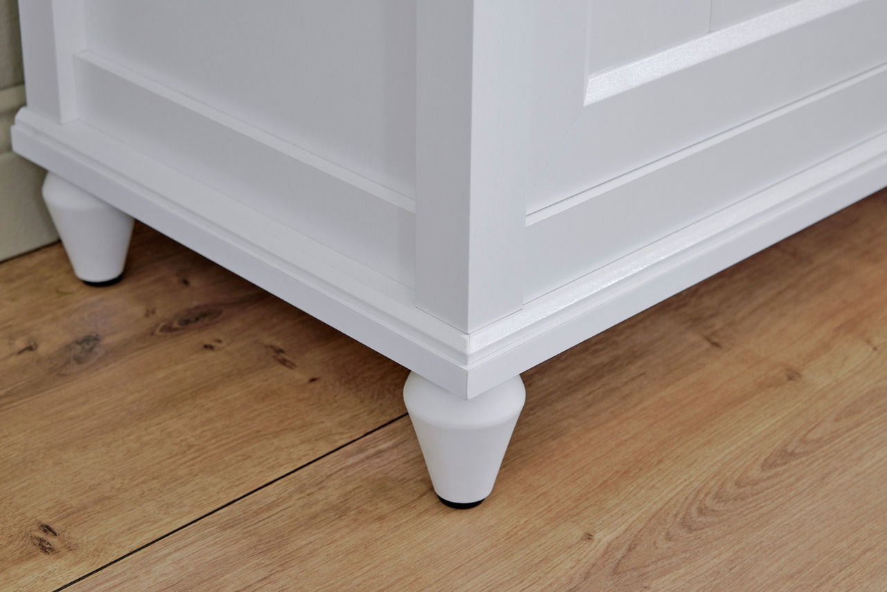 Nahaufnahme eines weißen Sideboards mit konischen Füßen auf einem Holzboden, seitliche Perspektive.