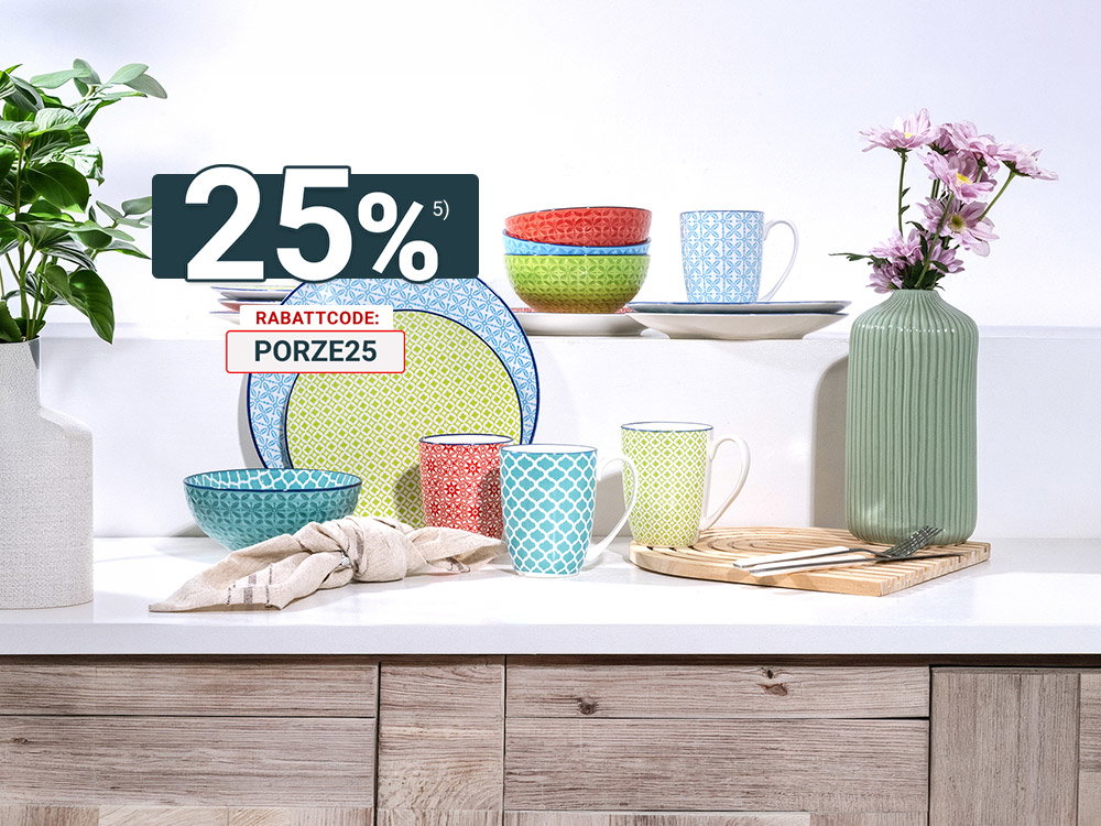Bunt gemischtes Geschirr mit Tassen, Schalen und Vase auf heller Küchenanrichte.
