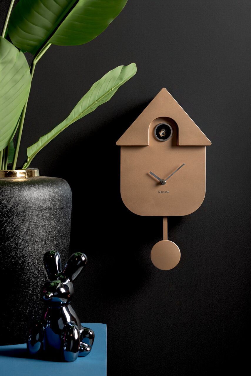 KARLSSON Wanduhr MODERN CUCKOO Moderne Wanduhr in Form eines Kuckucks mit Pendel, in einem eleganten Raum mit Pflanzen und Dekorationen, seitliche Perspektive.