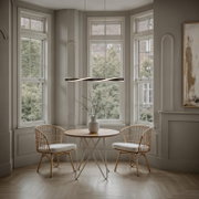 Moderne, gebogen LED-hanglamp in zwart met warmwit licht boven een ronde eettafel tussen twee stoelen voor grote ramen, vooraanzicht op ooghoogte