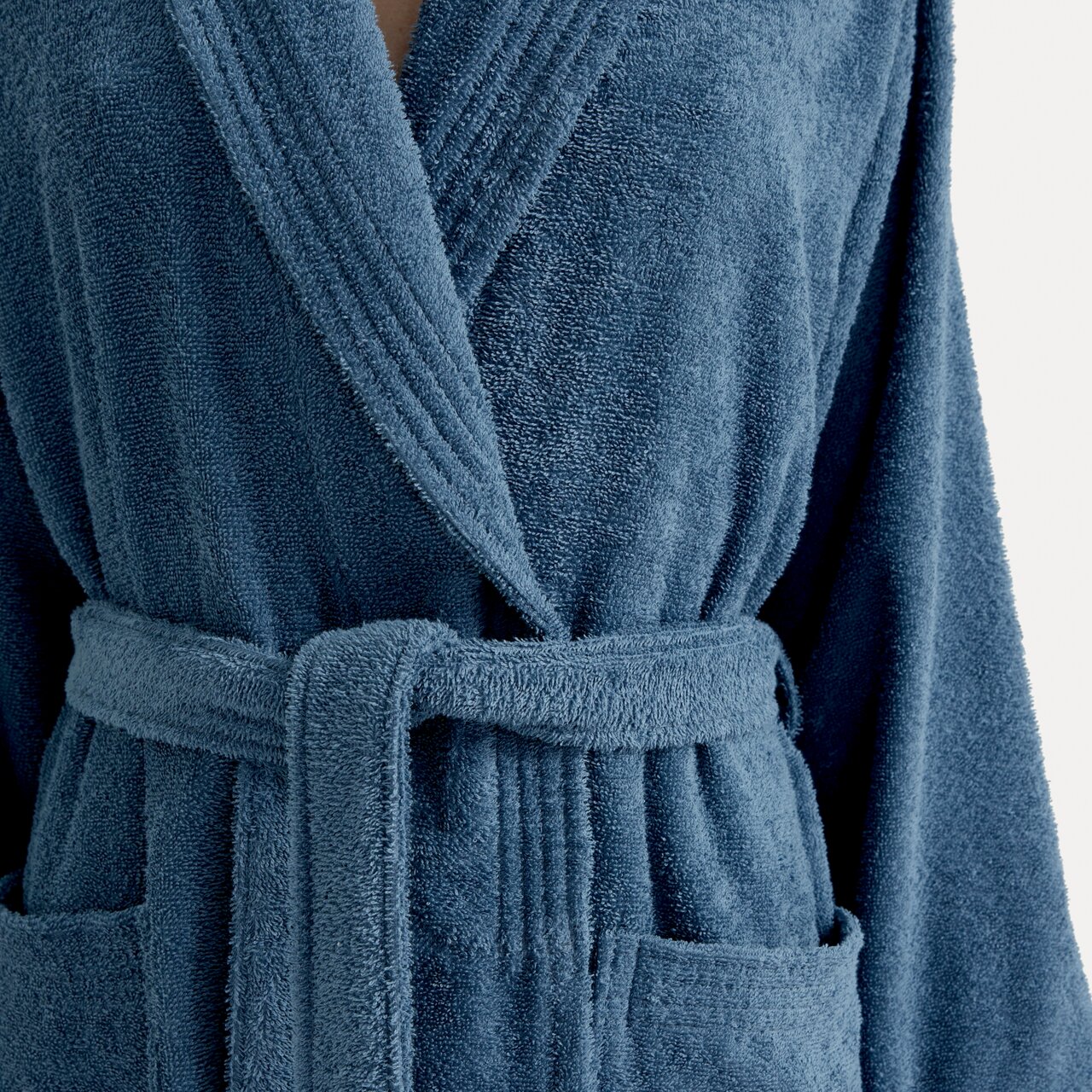 Nahaufnahme eines blauen Bademantels mit Schalkragen und Gürtel, Vorderansicht.