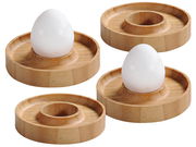 Vier runde Eierbecher aus Bambus, von oben betrachtet, mit zwei weißen Eiern in zwei der Becher.