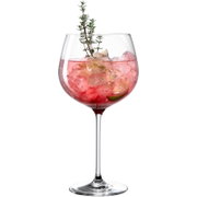 Frontalansicht eines großen bauchigen Weinglases mit rosafarbenem Cocktail, Eiswürfeln, Limettenscheibe und Thymianzweig vor weißem Hintergrund