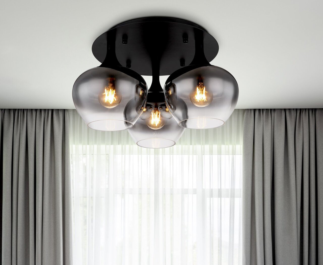 Globo Lighting Deckenleuchte MAXY Moderne Deckenleuchte MAXY mit drei rauchgrauen Glaskugeln, von unten betrachtet, vor einem Fenster mit Vorhängen.