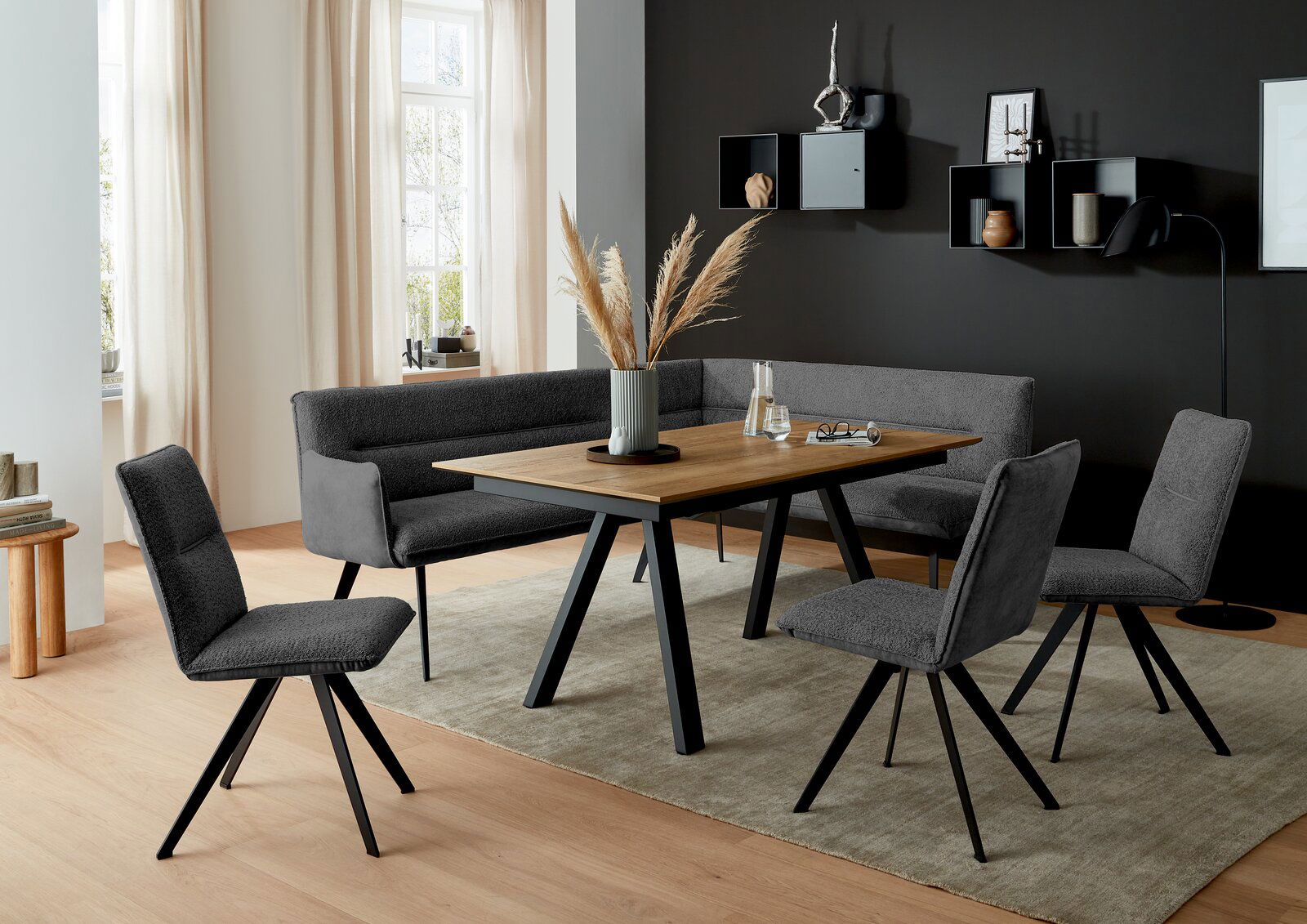 Moderner Esstisch mit Holzplatte und schwarzen Metallbeinen, umgeben von grauen Stühlen und einer Eckbank, in einem stilvoll eingerichteten Esszimmer mit Blick auf die Tischoberfläche.