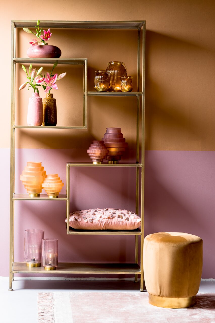 Offenes Regal mit goldfarbenem Rahmen, dekoriert mit rosa und goldenen Vasen und Kerzenhaltern, seitliche Perspektive.