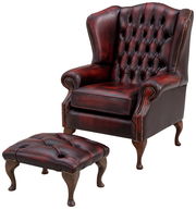 Ohrensessel aus dunkelrotem Leder mit Knopfheftung und passendem Hocker, seitliche Perspektive