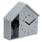Wanduhr in Form eines Hauses mit einem Hundekopf, der aus einer seitlichen Öffnung schaut, seitliche Perspektive