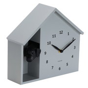 Wandklok in de vorm van een huis met een hondenkop die uit een opening aan de zijkant kijkt, zijaanzicht