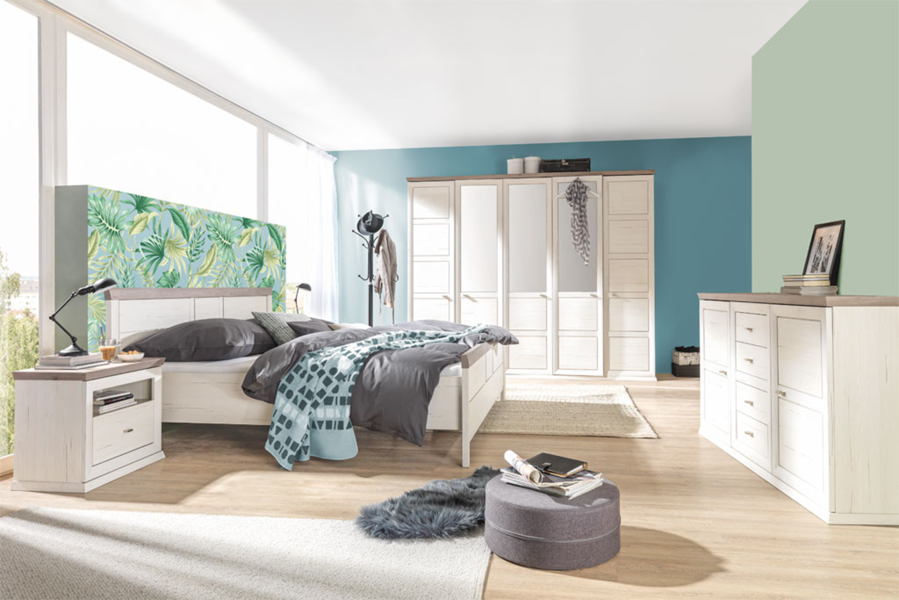 Modernes Schlafzimmer mit einem 180x200 cm großen Bett CAMRON, umgeben von stilvollen Möbeln in heller Holzoptik. Perspektive: seitliche Ansicht des Bettes mit Blick auf den Raum.