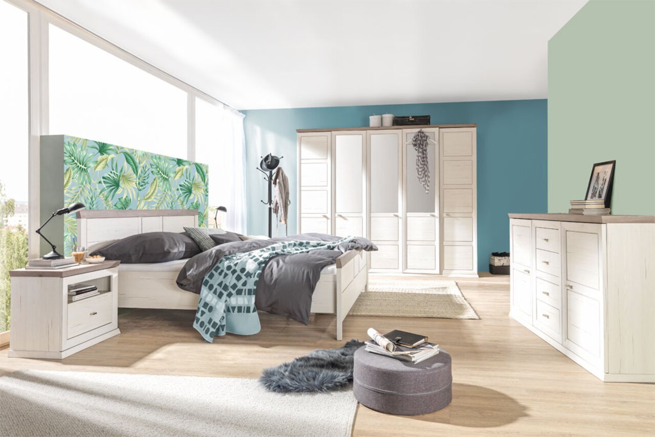 Modernes Schlafzimmer mit einem 180x200 cm großen Bett CAMRON, umgeben von stilvollen Möbeln in heller Holzoptik. Perspektive: seitliche Ansicht des Bettes mit Blick auf den Raum.