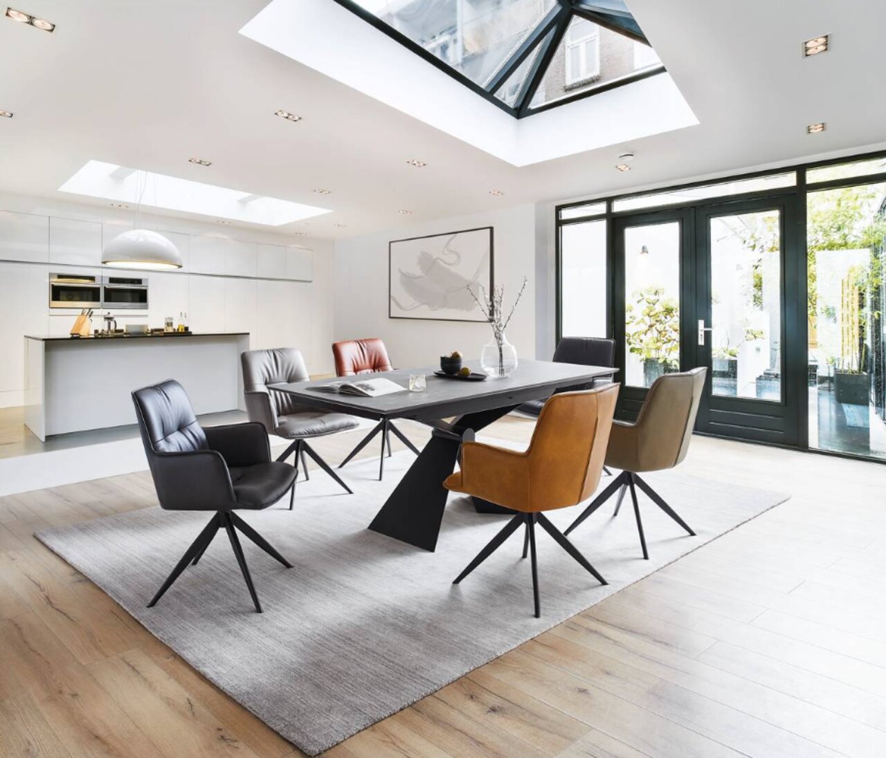 Moderner Essbereich mit Design-Schalensesseln in verschiedenen Farben um einen rechteckigen Tisch, fotografiert aus einer leicht erhöhten Perspektive.